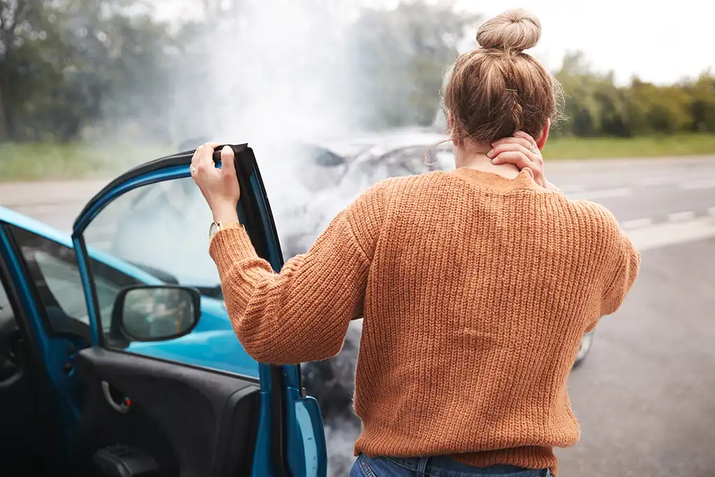 woman grabbing her neck after crashing her car