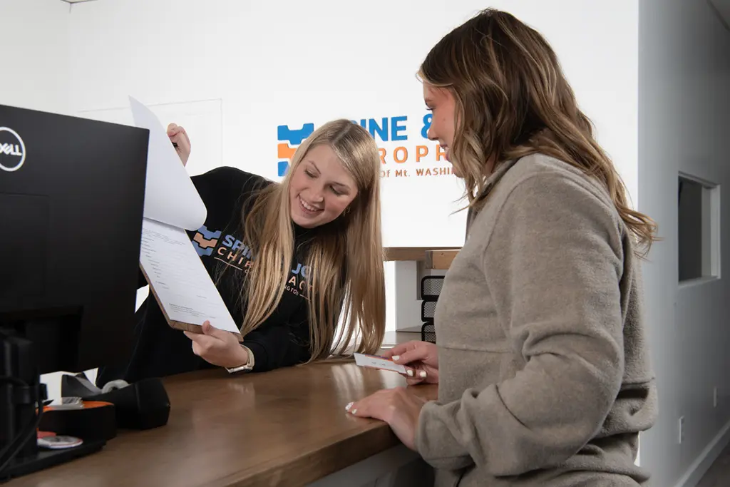 patient and staff at front desk of Spine & Joint Chiropractic